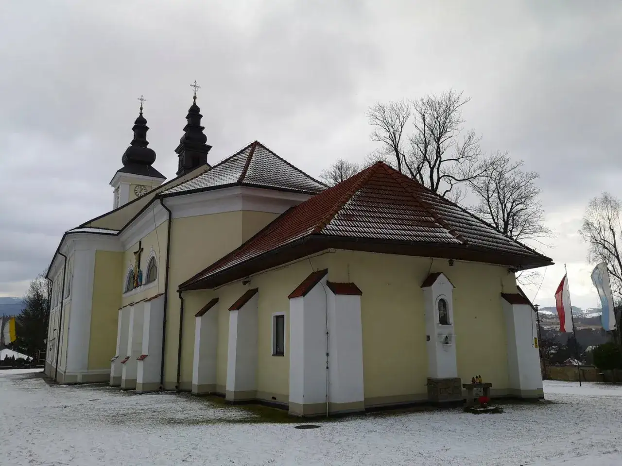Kościół z wieżami i zegarem, zimowy krajobraz. Maków Podhalański atrakcje turystyczne.