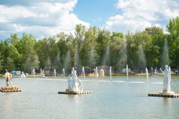 Park mitologii na wodzie z rzeźbami bogów i bogiń, otoczony zielenią i fontannami.