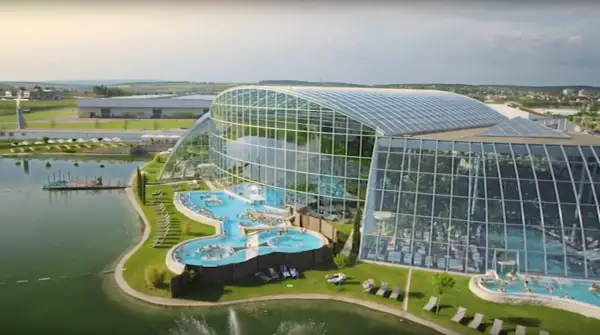 Nowoczesny park wodny pod Warszawą z basenami i palmami pod szklaną kopułą.