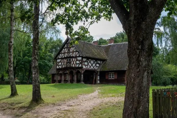 Drewniany dom z muru pruskiego i strzechą, otoczony zielenią. Jedna z atrakcji Olsztynka, zapraszająca do podróży w czasie.
