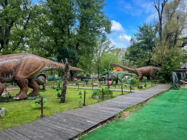 Spacer po parku z dinozaurami w Warszawie. Gigantyczne modele prehistorycznych stworzeń wśród zieleni i drewnianych ścieżek.