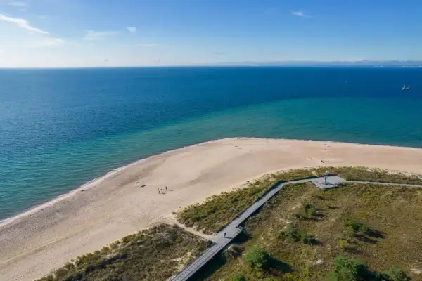 Piękna plaża i morze na Helu. Warto zobaczyć to miejsce, gdzie drewniana kładka prowadzi przez wydmy do piaszczystego brzegu.