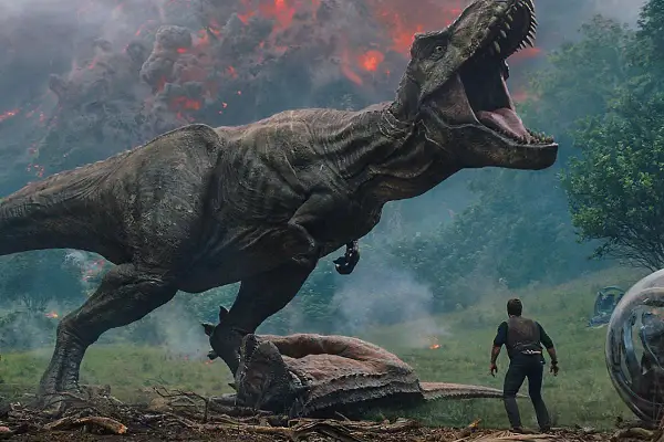 Tyranozaur atakuje w parku rozrywki Jurassic World, człowiek stoi w obliczu chaosu, w tle wulkaniczna erupcja.