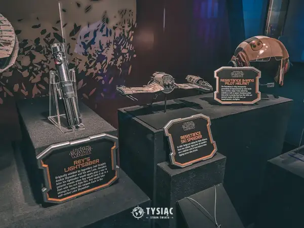 Miecz świetlny Rey, hełm pilota A-winga i pojazd Resistance Ski Speeder z wystawy Star Wars Galaxy's Edge.