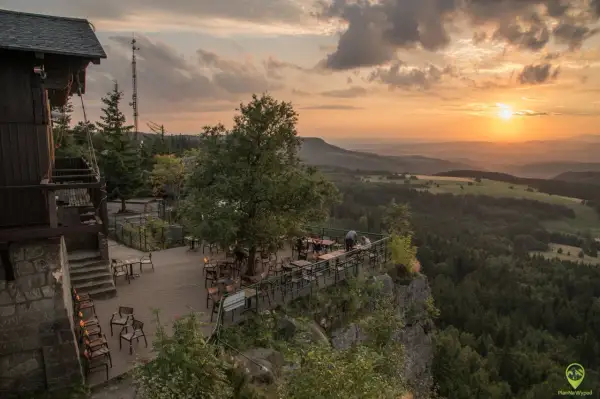 Widok z tarasu restauracji na malowniczą kotlinę kłodzką o zachodzie słońca.