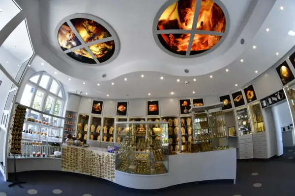 Wnętrze muzeum bursztynu Kołobrzeg. W gablotach błyszczą złote ozdoby, a na suficie widnieją okrągłe iluminacje z bursztynem.