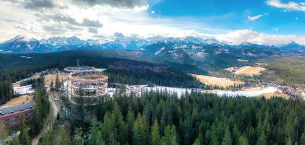Drewniana konstrukcja sky walk w Poroninie wznosi się nad lasem, oferując widok na ośnieżone Tatry.