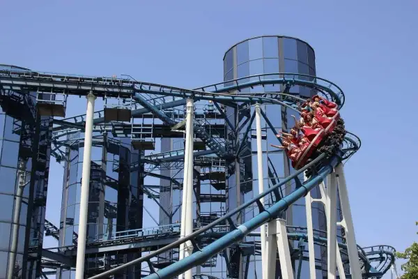 Wesoła kolejka górska z pasażerami wjeżdża na szczyt przy nowoczesnych budynkach w Europa Park Niemcy.