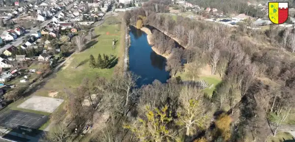 Widok z lotu ptaka na park drogowskazów w Witnicy. Jezioro, boisko, korty tenisowe i zabudowania mieszkalne.