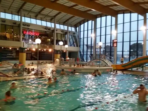 Ludzie pluskają się w basenie Warszawianka. W tle widać zjeżdżalnię i restaurację Bostonport.