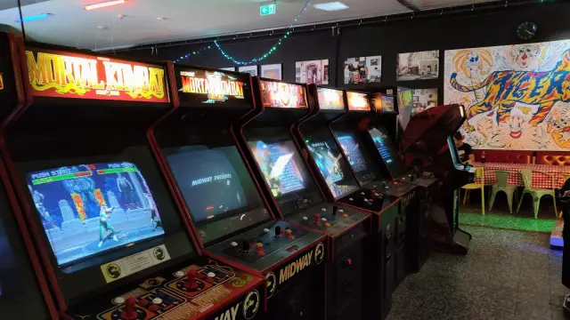 Rząd klasycznych automatów do gier, w tym Mortal Kombat, w sali gier.